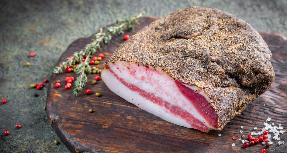 이탈리아 전통 가공육 관찰레 조각, 돼지 볼살 부위로 지방층이 두껍고 표면에 후추가 덮인 모습